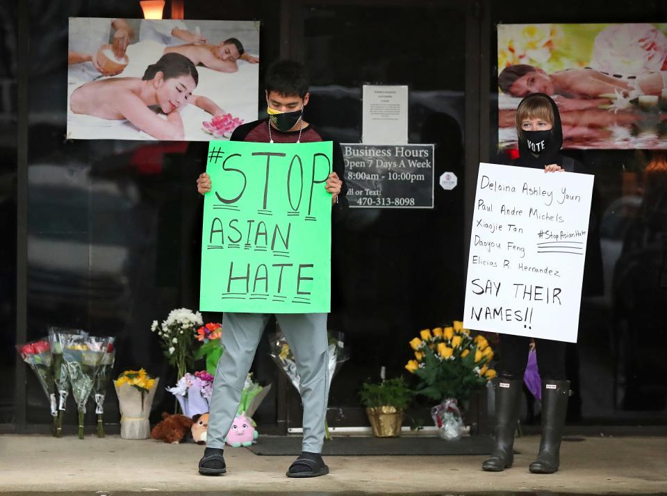 After dropping off flowers Jesus Estrella, left, and Shelby S., right, stand in support of the Asian and Hispanic community outside Youngs Asian Massage parlor where four people were killed, March 17, 2021, in Acworth, Ga. 