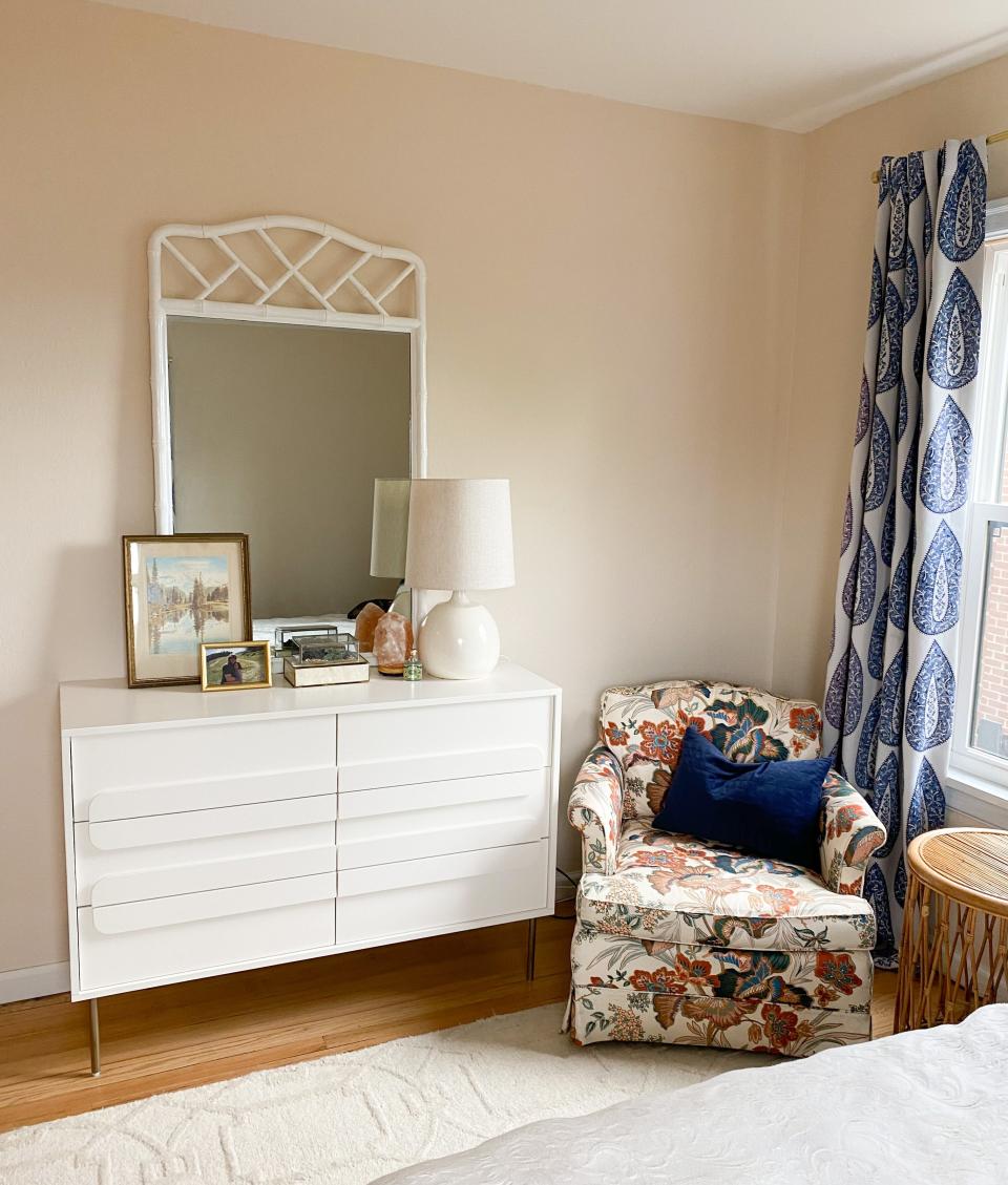 The modern dresser from West Elm looks sharp next to an inherited armchair. The dresser is topped with a vintage mirror and jewelry boxes, artwork inherited from a grandmother, a treasured photo and a vintage lamp with a new shade.
