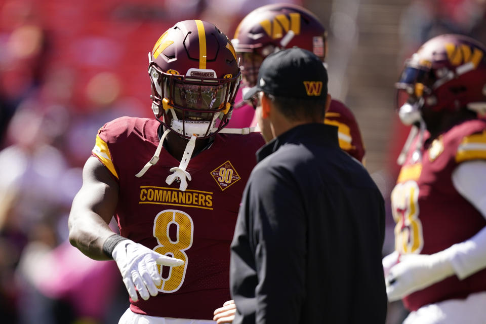 Washington Commanders running back Brian Robinson Jr., left, speaks with Commanders head coach Ron Rivera before an NFL football game against the Tennessee Titans, Sunday, Oct. 9, 2022, in Landover, Md. (AP Photo/Alex Brandon)