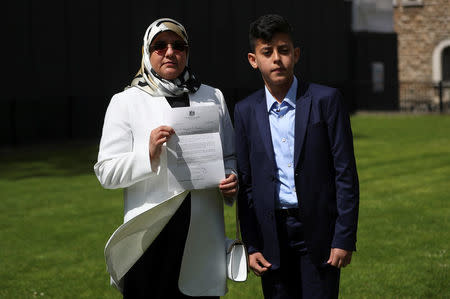 Fatima Boudchar, wife of Libyan politician Hakim Belhadj, stands with their son Abderrahim, as she holds a letter of apology from Prime Minister Theresa May outside the Houses of Parliament in Westminster, London, Britain, May 10, 2018. REUTERS/Hannah McKay