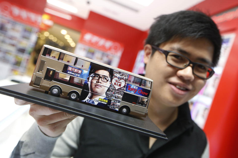 In this Dec. 9, 2013 photo, English grammar tutor Tony Chow, shows his advertising plan with a model of a double decker bus having his face plastered on the sides as to raise his profile further in Hong Kong. The 30-year-old teaches English grammar to thousands of secondary school pupils, who attend his after-school lessons or watch video replays of them at Modern Education’s 14 branches. Chow is a celebrity tutor in Hong Kong, where there’s big money to be made offering extracurricular lessons to parents desperately seeking an edge for their children preparing for the city’s intense public entrance exam for university. (AP Photo/Kin Cheung)