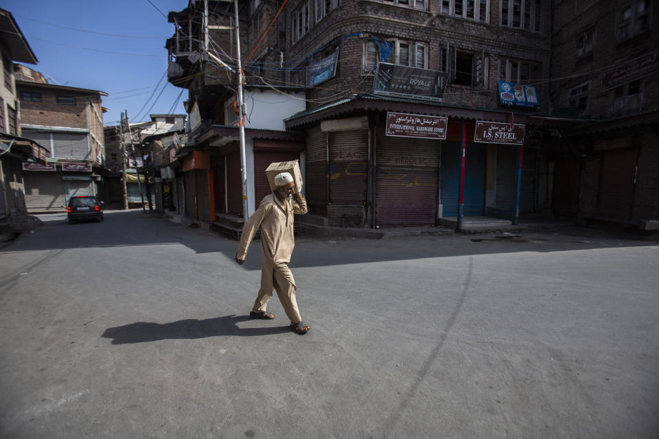 A Kashmiri man walks carrying a box through a closed market in Srinagar, Indian controlled Kashmir, Sunday, Sept. 5, 2021. Authorities Sunday eased some restrictions that had been imposed after the death of top resistance leader Syed Ali Geelani. However, most shops and businesses stayed closed as government forces patrolled roads and streets in the city. (AP Photo/Mukhtar Khan)