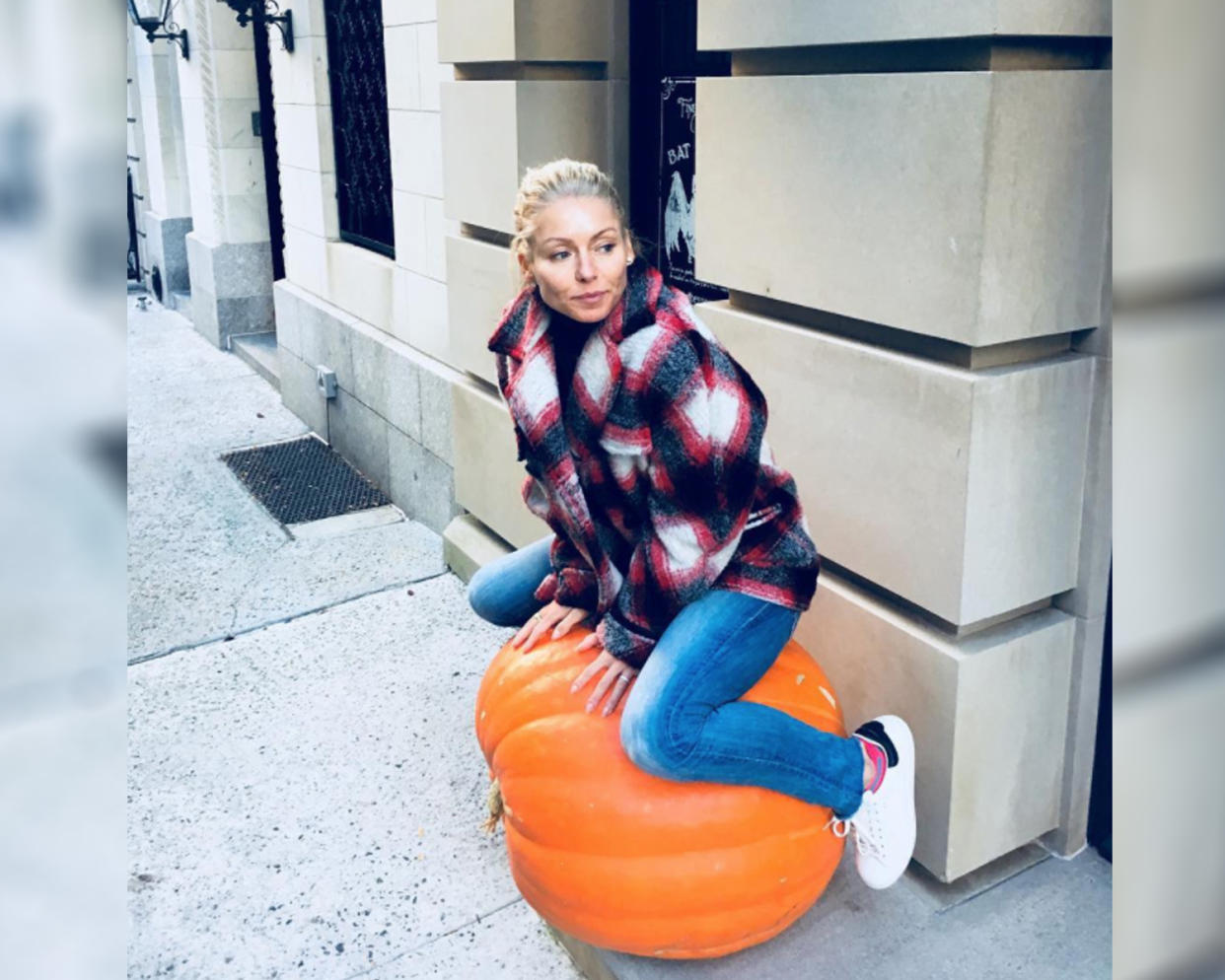 Kelly Ripa poses on a pumpkin. (Photo: Instagram/instasuelos)