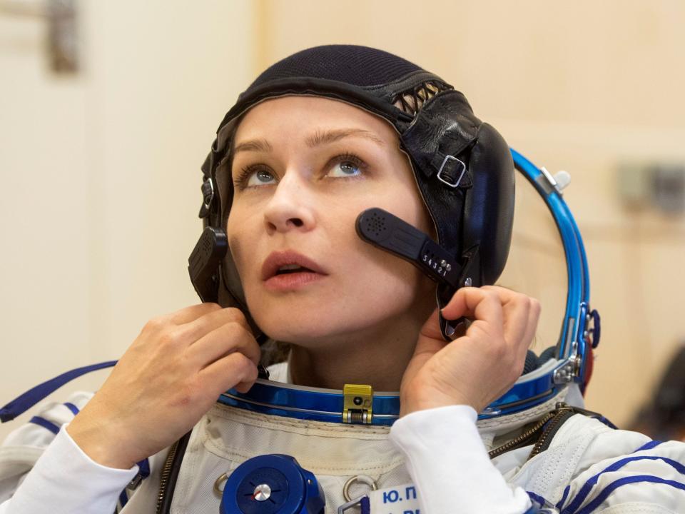 yulia peresild adjusts spacesuit neck line headset