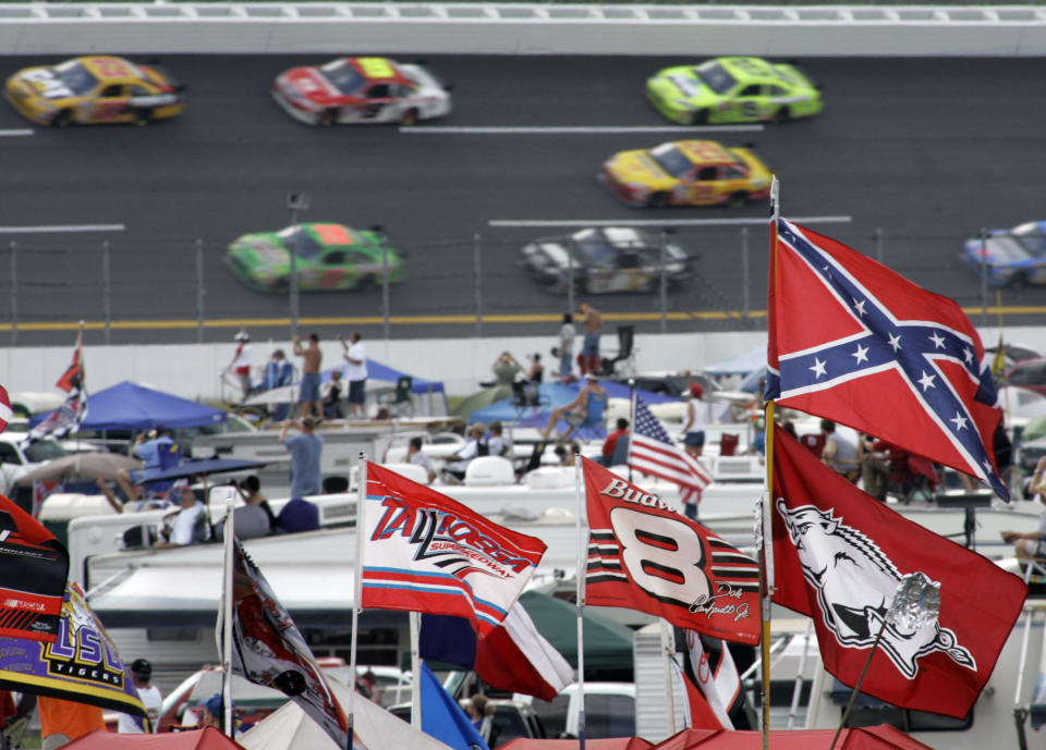 FILE - In this Oct. 7, 2007, file photo, a Confederate flag flies in the infield as cars come out of Turn 1 during a NASCAR auto race at Talladega Superspeedway in Talladega, Ala. NASCAR banned the Confederate flag from its races and venues Wednesday, June 10, 2020, formally severing itself from what for many is a symbol of slavery and racism. (AP Photo/Rob Carr, File)