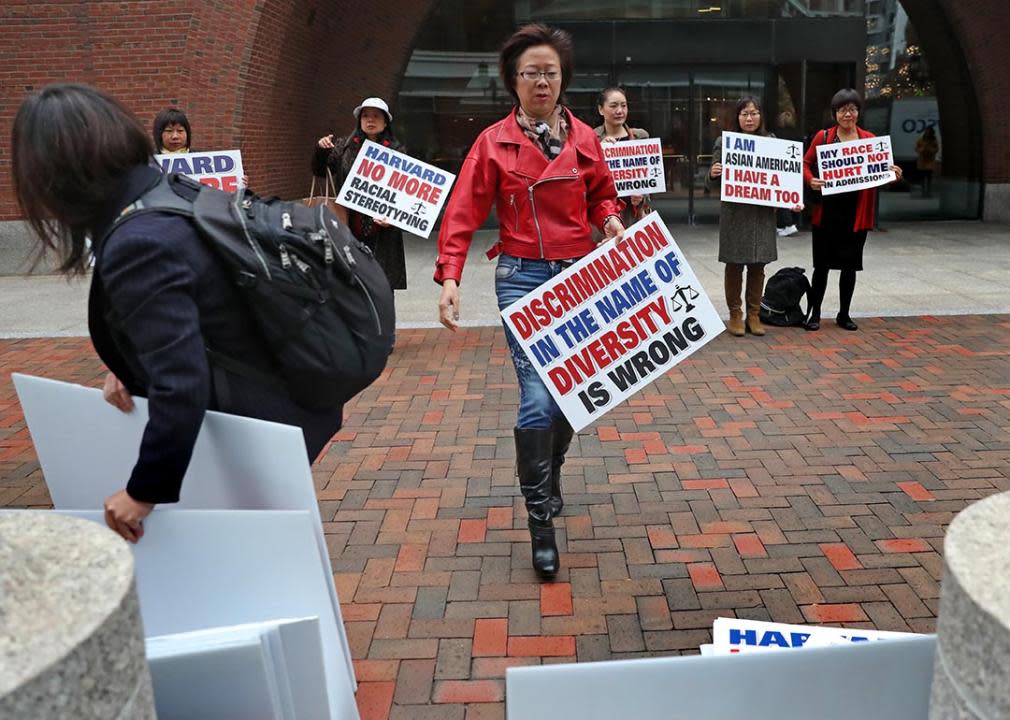 Ping Zhang holds a sign while demonstrating outside the John Joseph Moakley United States Courthouse on the opening day of Harvard University's affirmative action