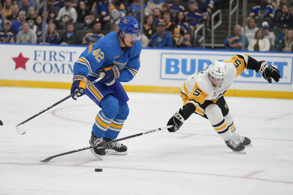 St. Louis Blues' Kasperi Kapanen (42) and Pittsburgh Penguins' Ryan Shea (5) battle for a loose puck during the second period of an NHL hockey game Saturday, Oct. 21, 2023, in St. Louis. (AP Photo/Jeff Roberson)