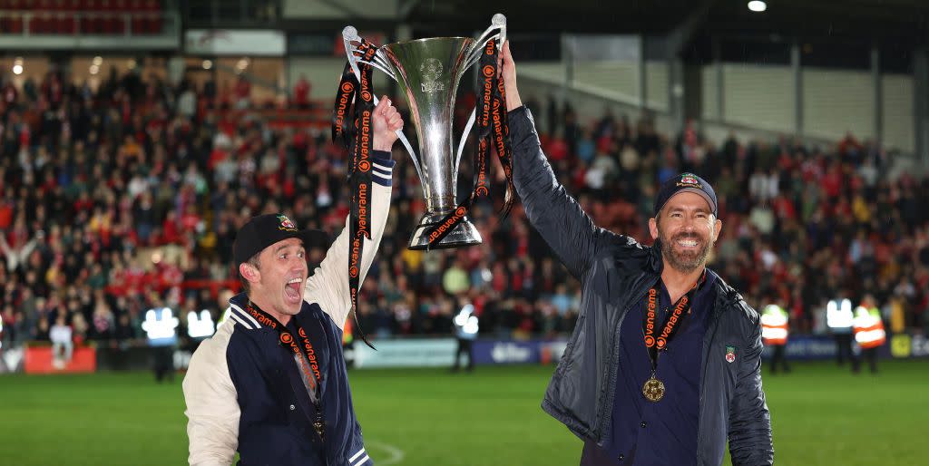 rob mcelhenney and ryan reynolds hold the wrexham trophy