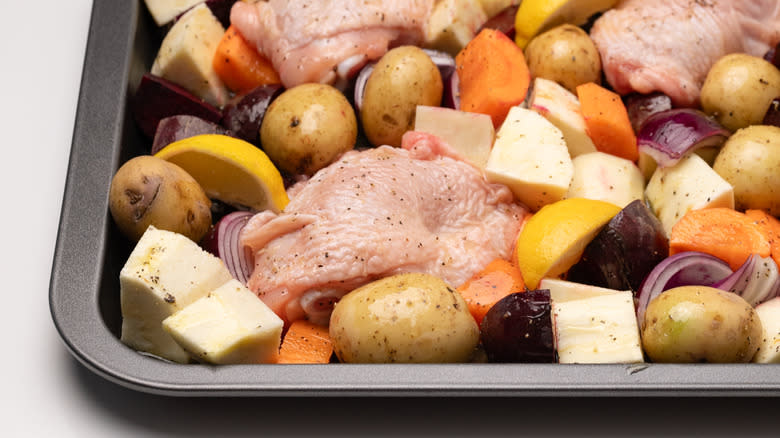 uncooked chicken and vegetables on sheet pan