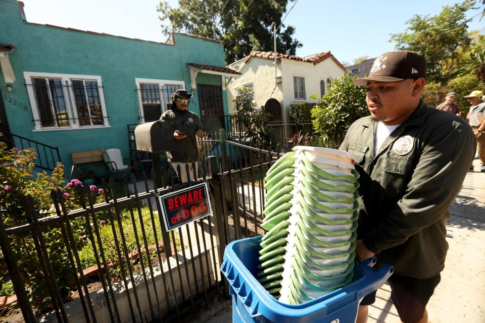 A man carries pails past houses