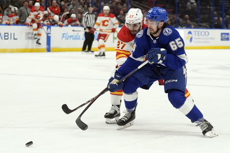 Tampa Bay Lightning defenseman Maxwell Crozier (65) gets tied up by Calgary Flames right wing Matt Coronato (27) during the first period of an NHL hockey game Thursday, March 7, 2024, in Tampa, Fla. (AP Photo/Chris O'Meara)