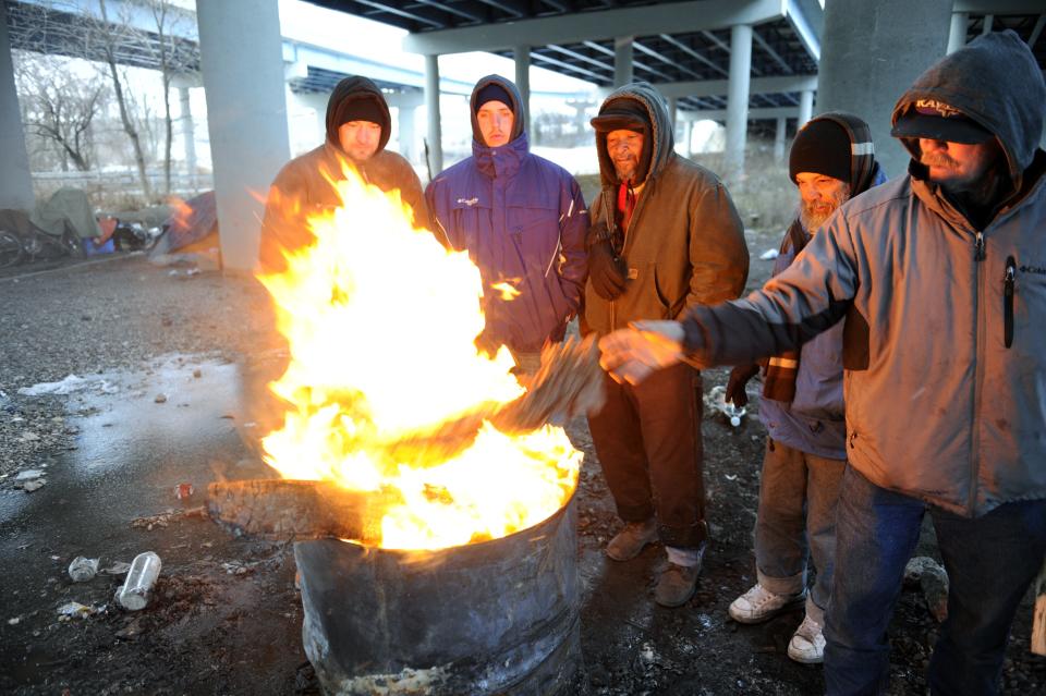 Michael Best, right, and others who identified themselves as homeless, use donated wood and a fire barrel to keep warm Monday, Jan. 6, 2014, in Knoxville, Tenn. Monday's expected high temperature in Knoxville of around 24 degrees came hours before dawn, and is expected to fall into the single digits for most of East Tennessee. (AP Photo/Knoxville News Sentinel, Michael Patrick)