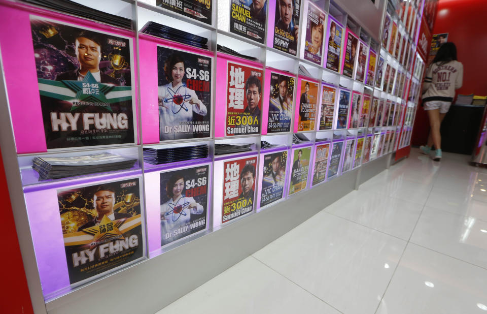 In this Dec. 9, 2013 photo, a student walks near the leaflets displaying profiles of the celebrity tutors in the tutorial academy "Modern Education" in Hong Kong. Tony Chow, a 30-year-old, teaches English grammar to thousands of secondary school pupils, who attend his after-school lessons or watch video replays of them at Modern Education’s 14 branches. Chow is a celebrity tutor in Hong Kong, where there’s big money to be made offering extracurricular lessons to parents desperately seeking an edge for their children preparing for the city’s intense public entrance exam for university. (AP Photo/Kin Cheung)