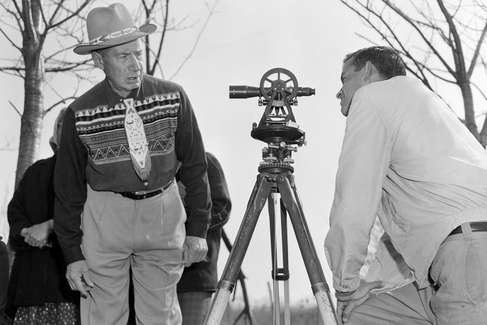 FILE - In this April 18, 1958 file photo, Philip N. Brooks, right, a New York State surveyor, takes a look through his transit on the Tuscarora Indian Reservation near Niagara Falls, N.Y., while Tuscarora Chief Elton Black Cloud Greene watches. The tribe is resisting state seizure of their land for a power project. In 1959, the U.S. government started the switch from the U.S. survey foot to the international foot, and it will finish the job in 2022. (AP Photo)