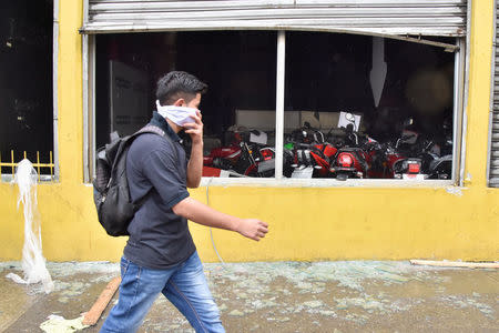 A man walks past a motorcycle dealership vandalized by supporters of Salvador Nasralla, presidential candidate for the Opposition Alliance Against the Dictatorship, during a protest caused by the delayed vote count for the presidential election in San Pedro Sula, Honduras December 1, 2017. REUTERS/Moises Ayala