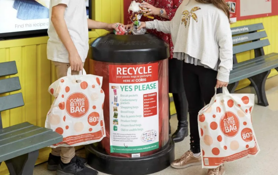 A REDcycle bin being used by three people holding Coles bags.