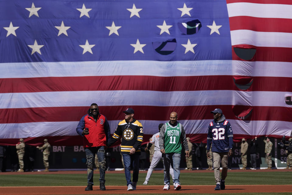 Former Red Sox designated hitter David Ortiz, left, walks onto the field with former Boston Bruin Shawn Thornton, former Boston Celtic Dana Barros and former New England Patriot Devin McCourty, from left, prior to a baseball game against the Baltimore Orioles on opening day at Fenway Park, Thursday, March 30, 2023, in Boston. (AP Photo/Charles Krupa)