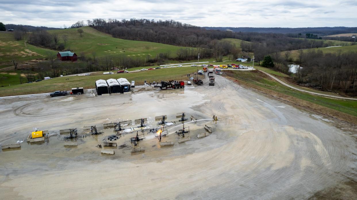 Firefighters work to control an oil wellhead fire at the CHK Jamar Pad owned and maintained by Encino Energy in North Township, Harrison County. The fire was called in early Tuesday morning. Equipment from multiple area fire departments can be seen in the background as water from Bowerston was shuttled to the scene.