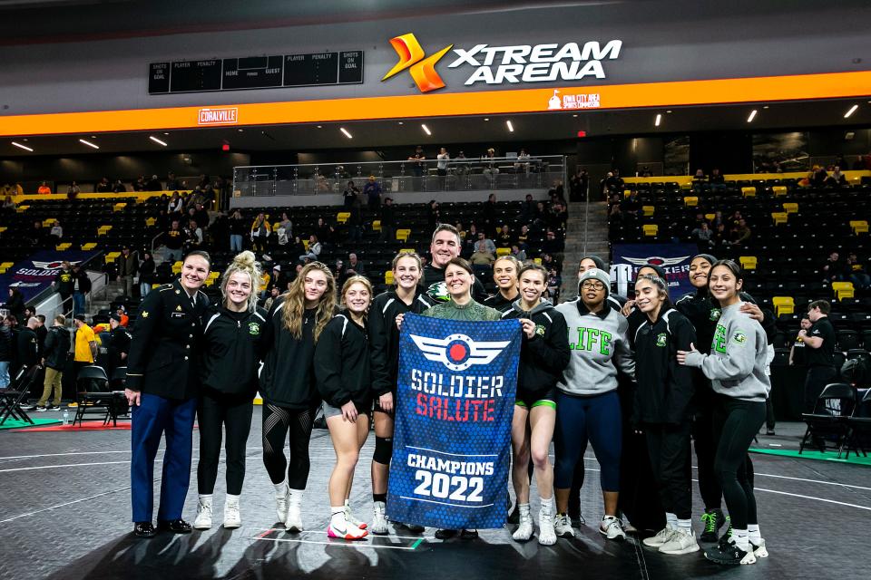 Members of the Life University women's wrestling team pose for a photo with their championship banner in the finals during the Soldier Salute college wrestling tournament.