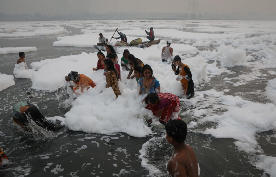 People bathe amidst the foam covering the polluted Yamuna river on a smoggy morning in New Delhi, India November 8, 2021. REUTERS/Anushree Fadnavis