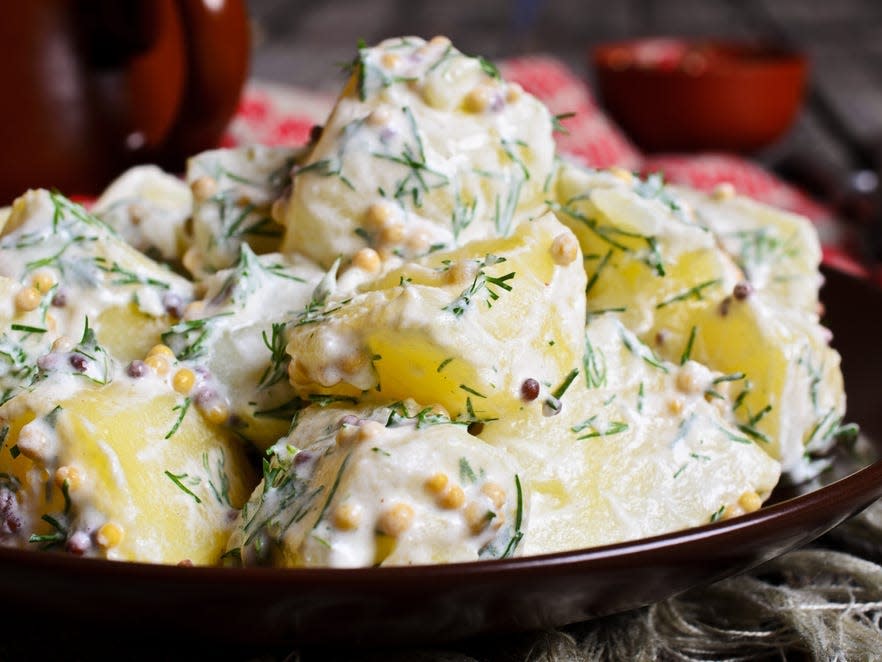 a bowl of potato salad with mustard and dill