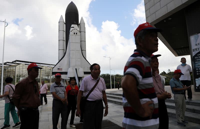People stand in front of a scaled model of the Challenger space shuttle at a space science museum in Wenchang, Hainan
