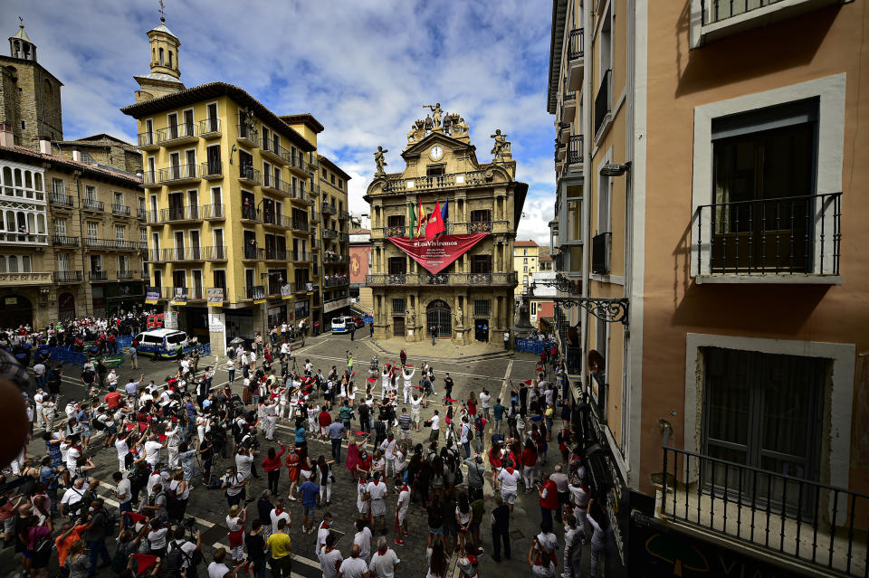 Residents, wearing white clothes and traditional red scarves, take to the streets on the day the ''txupinazo'' would usually take place to start the famous San Fermin festival, which was due canceled this year by the conoravirus, in Pamplona, northern Spain, Monday, July 6, 2020. (AP Photo/Alvaro Barrientos)