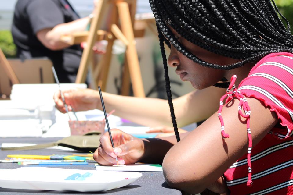 A teen uses a brush to paint during Juneteenth Day celebration at Joannes Park, Saturday, June 18, 2022, in Green Bay.