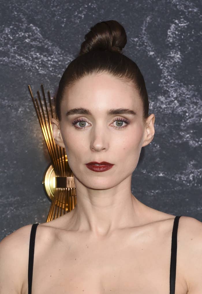 A close-up of Rooney Mara who's rocking a top-knot bun and dark lipstick an an event