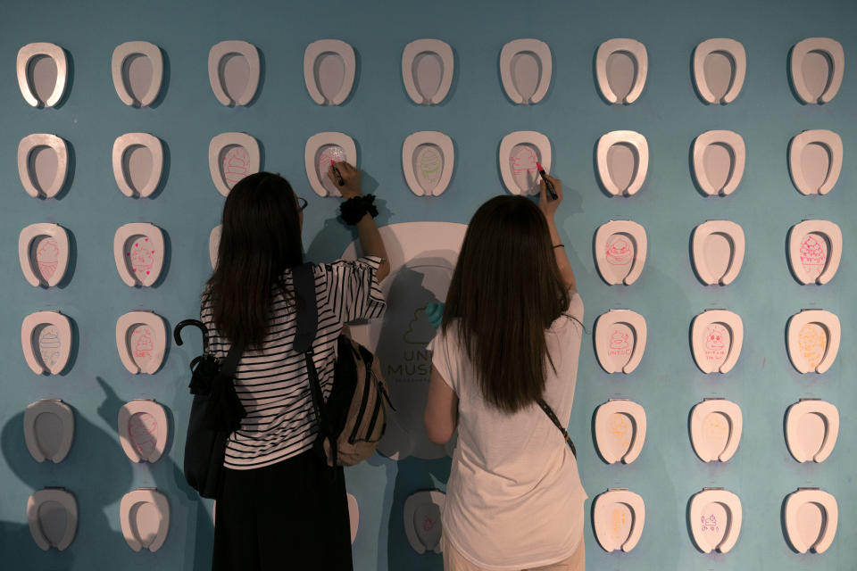 In this Tuesday, June 18, 2019, photo, two women draw on toilet-shaped boards at the Unko Museum in Yokohama, south of Tokyo. In a country known for its cult of cute, even poop is not an exception. A pop-up exhibition at the Unko Museum in the port city of Yokohama is all about unko, a Japanese word for poop. The poop installations there get their cutest makeovers. They come in the shape of soft cream, or cupcake toppings. (AP Photo/Jae C. Hong)