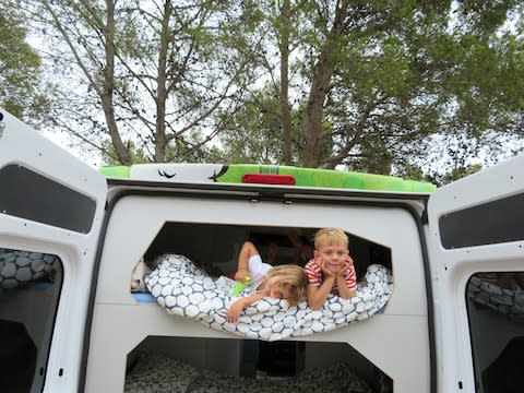 Two for the road: Hattie Garlick's children look out from their bunk in the van - Credit: Hattie Garlick