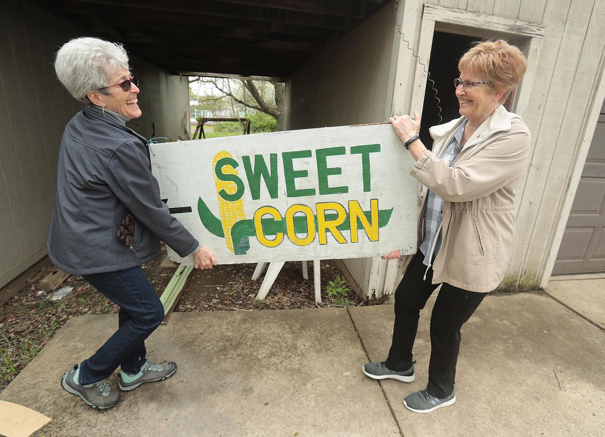 Sisters Barbie Ream, left, and Debbie Sprit, carry a sweet corn sign off their family property that they want to keep from being sold at an upcoming auction of their longtime family homestead.