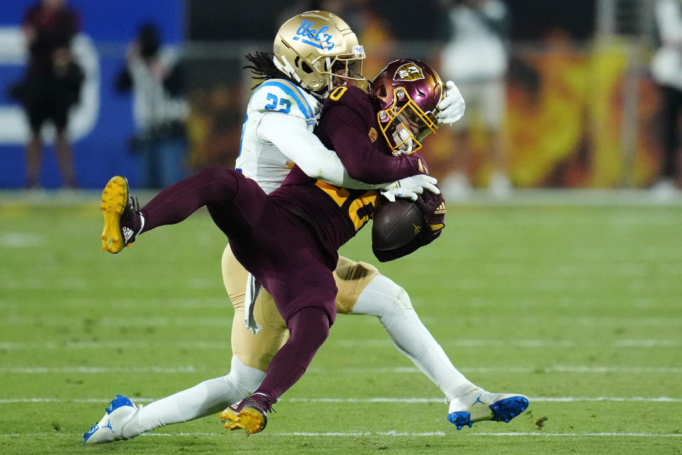 UCLA defensive back Azizi Hearn (22) takes down Arizona State wide receiver Giovanni Sanders (20) during the second half of an NCAA college football game in Tempe, Ariz., Saturday, Nov. 5, 2022. UCLA won 50-36. (AP Photo/Ross D. Franklin)