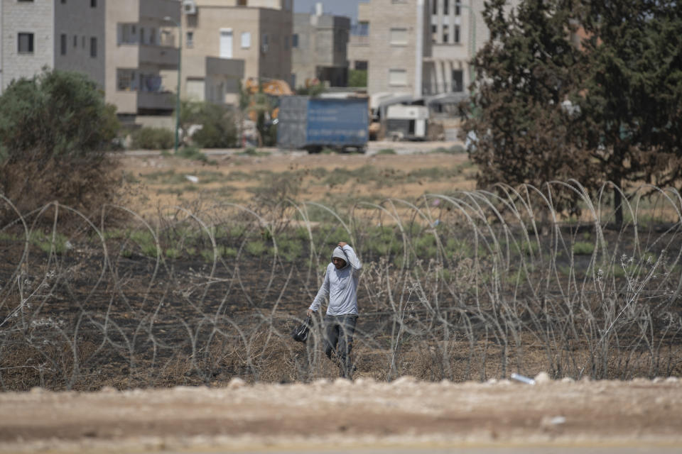 A Palestinian laborer crosses through a damaged section of the Israeli separation fence, as he returns home after a days work in Israel, in the West Bank village of Jalameh, near Jenin, Monday, Sept. 6, 2021. Israel launched a massive manhunt in the country's north and the occupied West Bank early Monday after six Palestinian prisoners tunneled out of their cell and escaped overnight from a high-security facility in an extremely rare breakout. (AP Photo/Nasser Nasser)