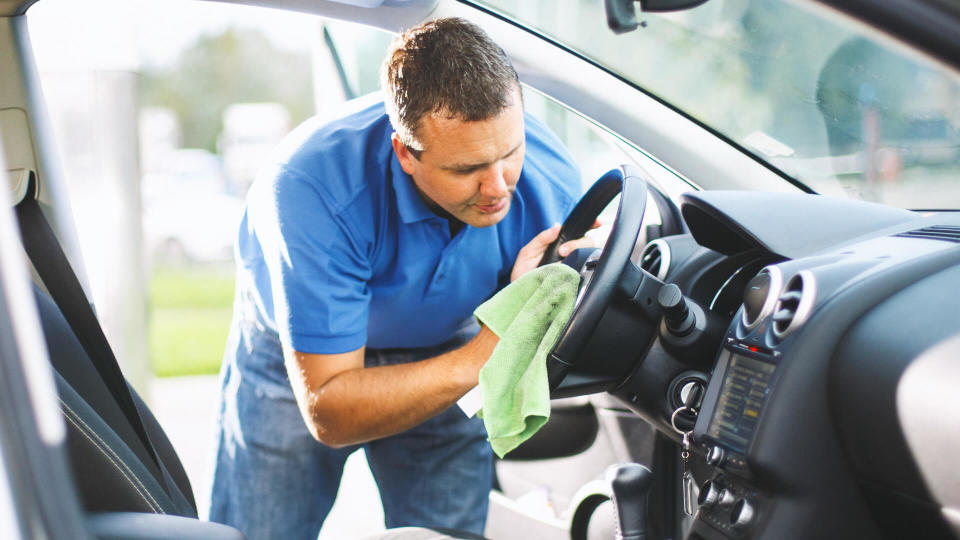 Closeup side view of mid 30's caucasian man cleaning upholstery of his car.