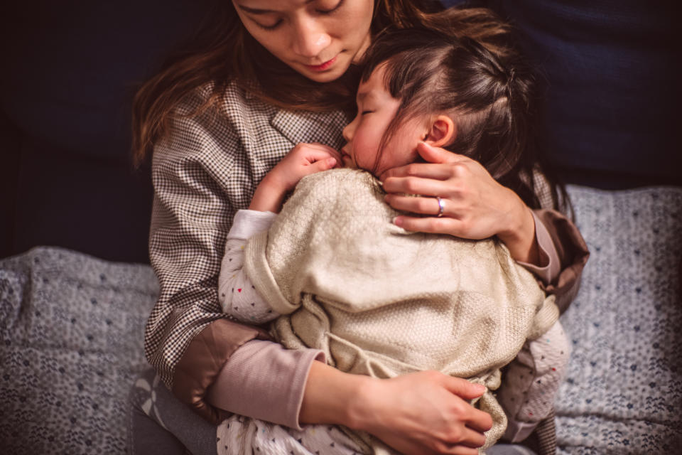 Top view of lovely little girl sleeping soundly under mom's arms at home