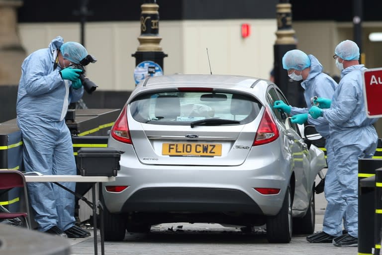 Police forensics officers work around a silver Ford Fiesta car that was driven into a barrier at the Houses of Parliament in London