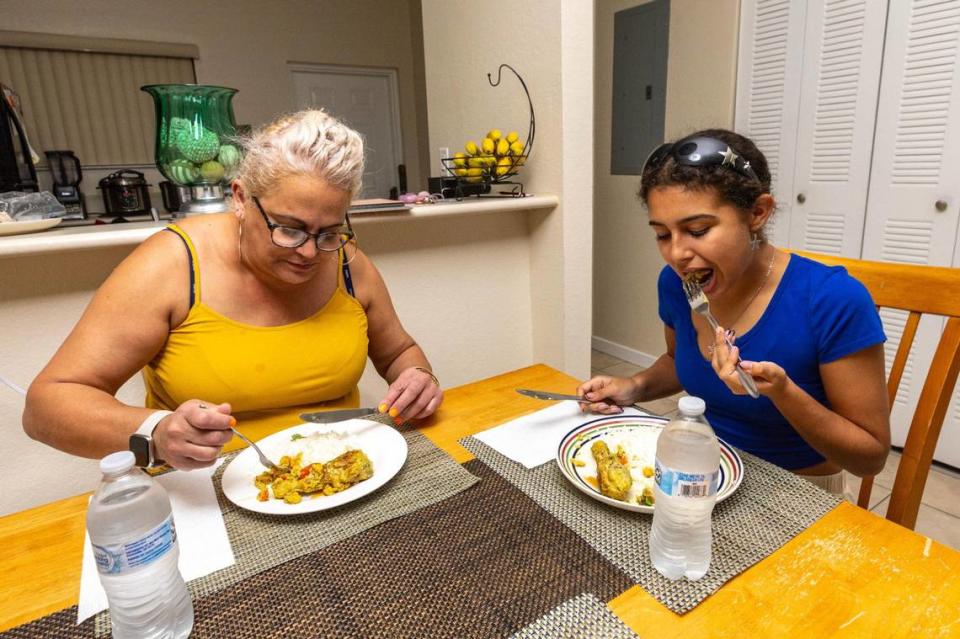 Mother and daughter Naylin Sanchez, 48, and Adrienne Rosquete, 15, eat their meals of One Pot Coconut Curried Chicken after a cooking class hosted by FIU School of Hospitality on how to cook healthy meals in real time, from their home at Verde Gardens, a 145-unit townhome community for formerly homeless residents, in Homestead, Florida, on Tuesday, October 24, 2023.