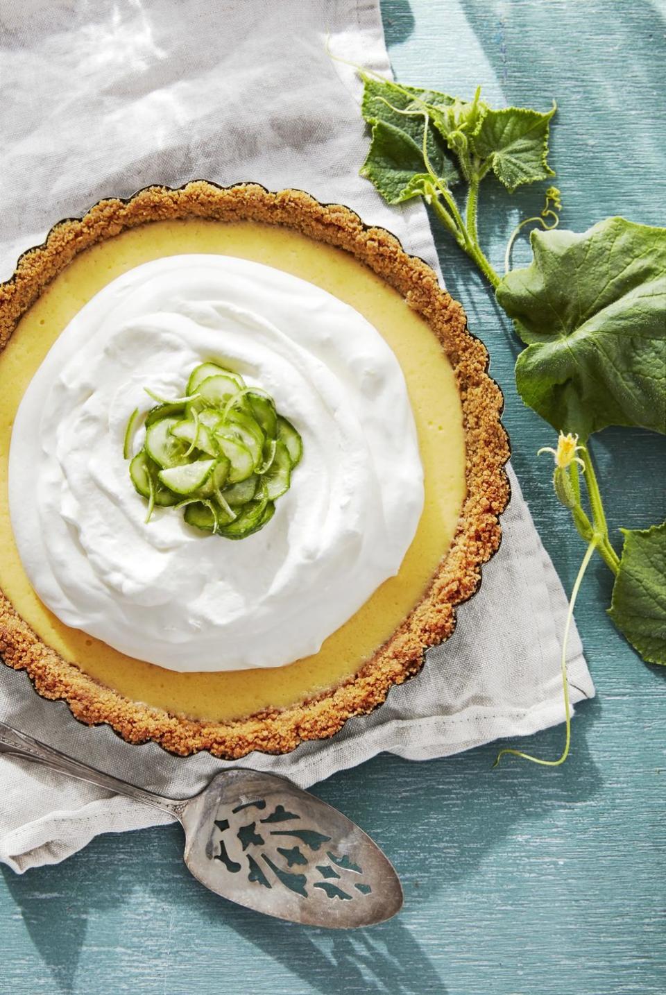 cucumber key lime pie in a baking dish with a mound of whipped cream and sliced cucumber garnish