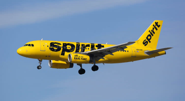 A yellow, Spirit Airlines (SAVE) branded airplane flying in the air