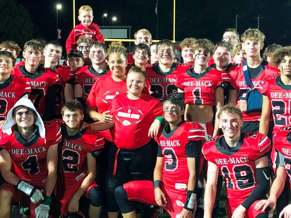 Lydia Zehr and her son, Carter (middle) surrounded by the Dee-Mack varsity football team after their 16-0 win over Gibson City on Friday, Sept. 1, 2023.