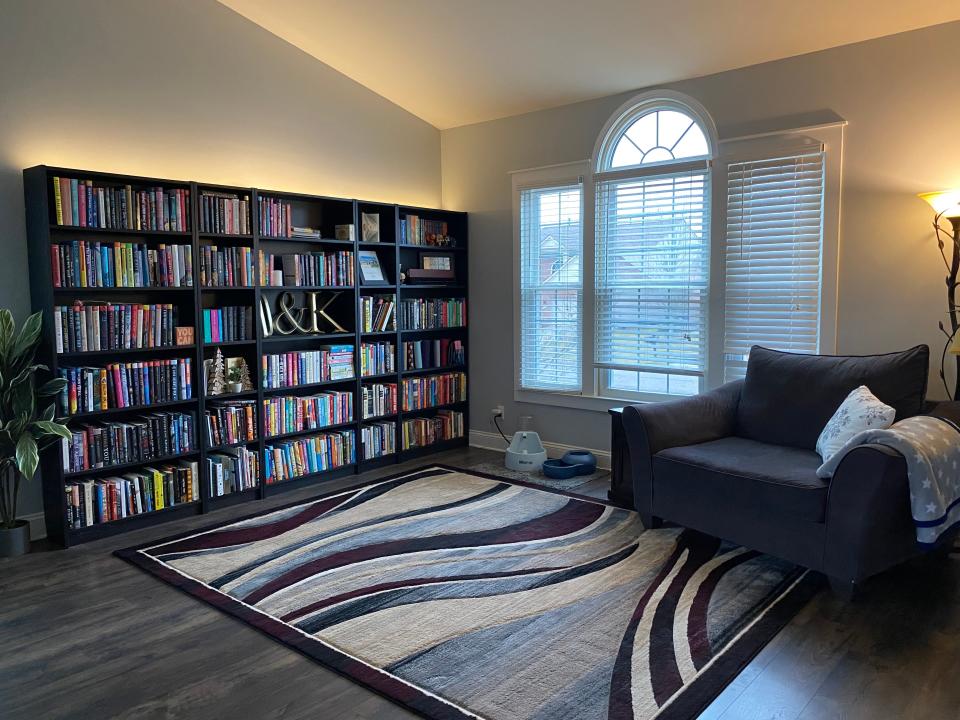 room with bookshelves along wall, light paint, and patterned blue rug