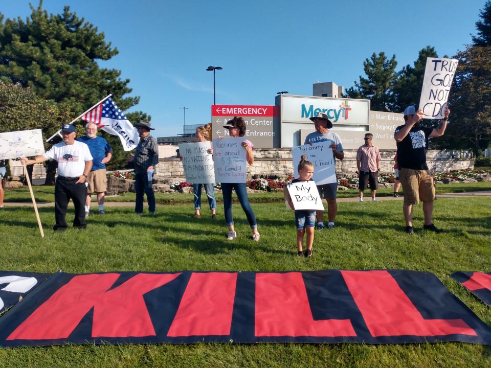 A girl and her mother protest Mercy Hospital in front of a banner saying "vaccines kill" in Springfield, Mo., on Aug. 14.