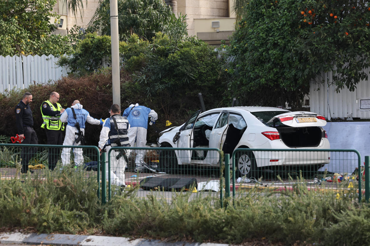 Les médecins légistes de la police israélienne inspectent une voiture endommagée après l’attaque à la voiture bélier, survenue dans le centre-ville de Raanana. 