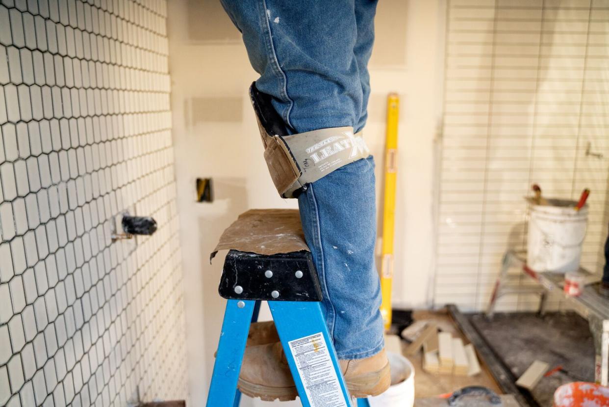 man on ladder installing tile