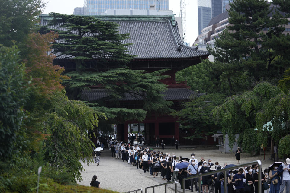 People wait in line before their prayers to pay respect for former Japanese Prime Minister Shinzo Abe at Zojoji temple before his funeral in Tokyo on Tuesday, July 12, 2022. Abe was assassinated Friday while campaigning in Nara, western Japan. (AP Photo/Hiro Komae)