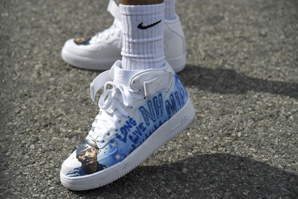 Slum Baby, of the Crenshaw neighborhood of Los Angeles, appears wearing shoes in tribute to Nipsey Hussle, whose given name was Ermias Asghedom, at the late rapper's Celebration of Life memorial service on Thursday, April 11, 2019, at the Staples Center in Los Angeles. (Photo by Chris Pizzello/Invision/AP)