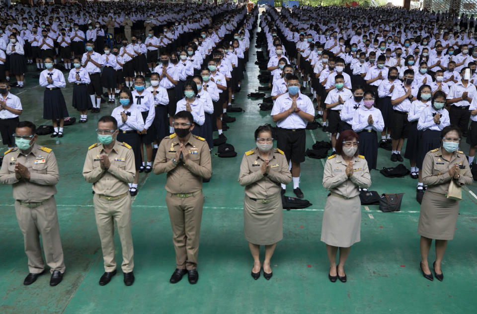 Teachers and students wearing protective gear to help curb the spread of the coronavirus as they pray before class at Samkhok School in Pathum Thani, outside Bangkok, Wednesday, July 1, 2020. Thailand has begun a fifth phase of relaxations of COVID-19 restrictions, allowing the reopening of schools and high-risk entertainment venues such as pubs and massage parlors that had been shut since mid-March. (AP Photo/Sakchai Lalit)