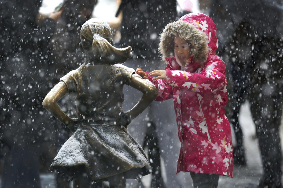 Una niña retira nieve del brazo de la estatua Fearless Girl en Manhattan el jueves 15 de noviembre del 2018, en Nueva York. (AP Foto/Wong Maye-E)