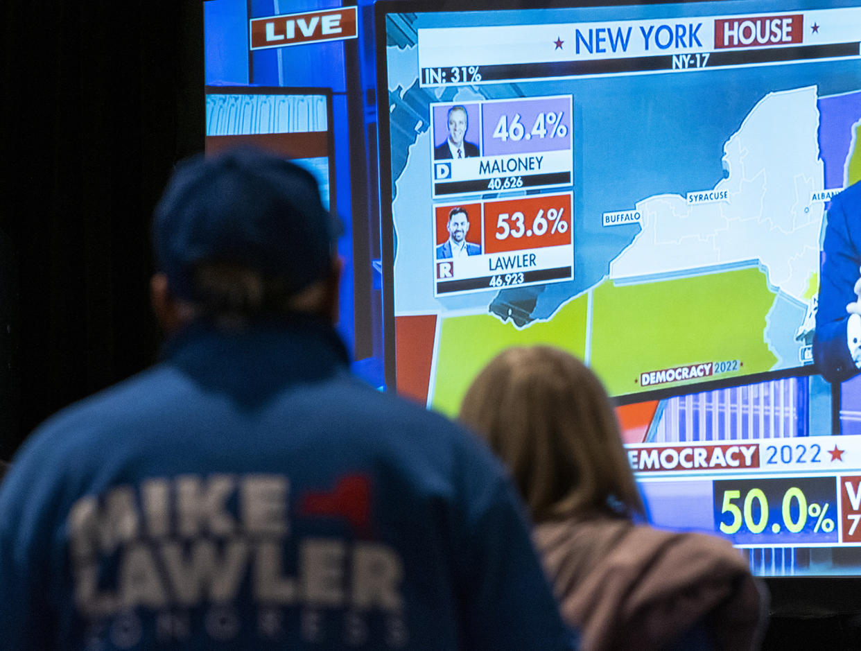Supporters of congressional candidate Mike Lawler watch the results on a large screen during an election night party.